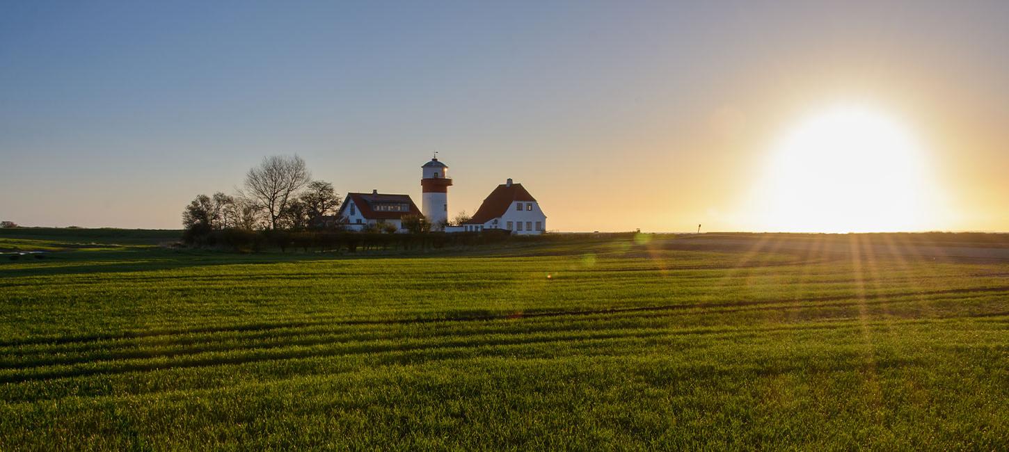 Solen står op på en dejlig forårsdag på Langeland og skinner over de grønner marker og fyrtårnet ved Hou,