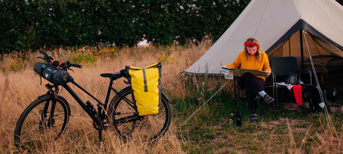 Kvinde sidder og kigger på et kort foran et glampingtelt