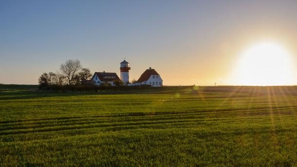 Solen står op på en dejlig forårsdag på Langeland og skinner over de grønner marker og fyrtårnet ved Hou,