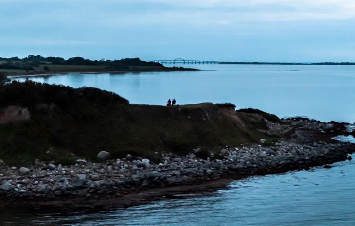 Par sidder på en bænk med udsigt over Langelandsbroen